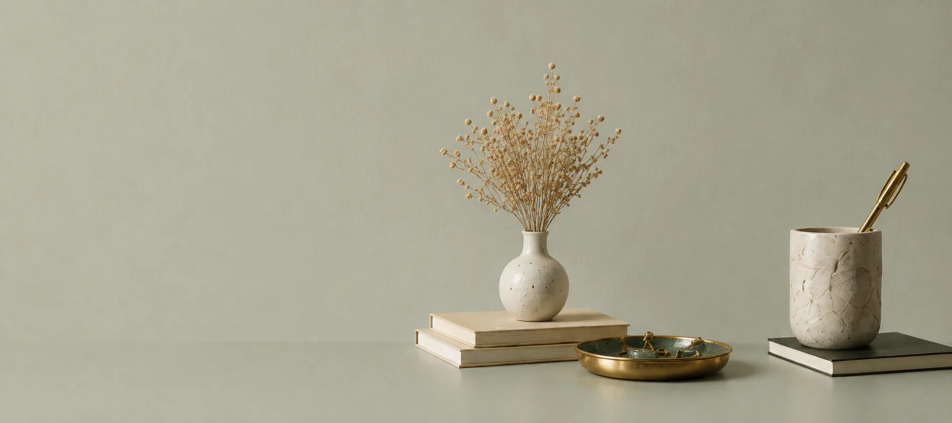 Dried flowers, books and a brass tray on a desk