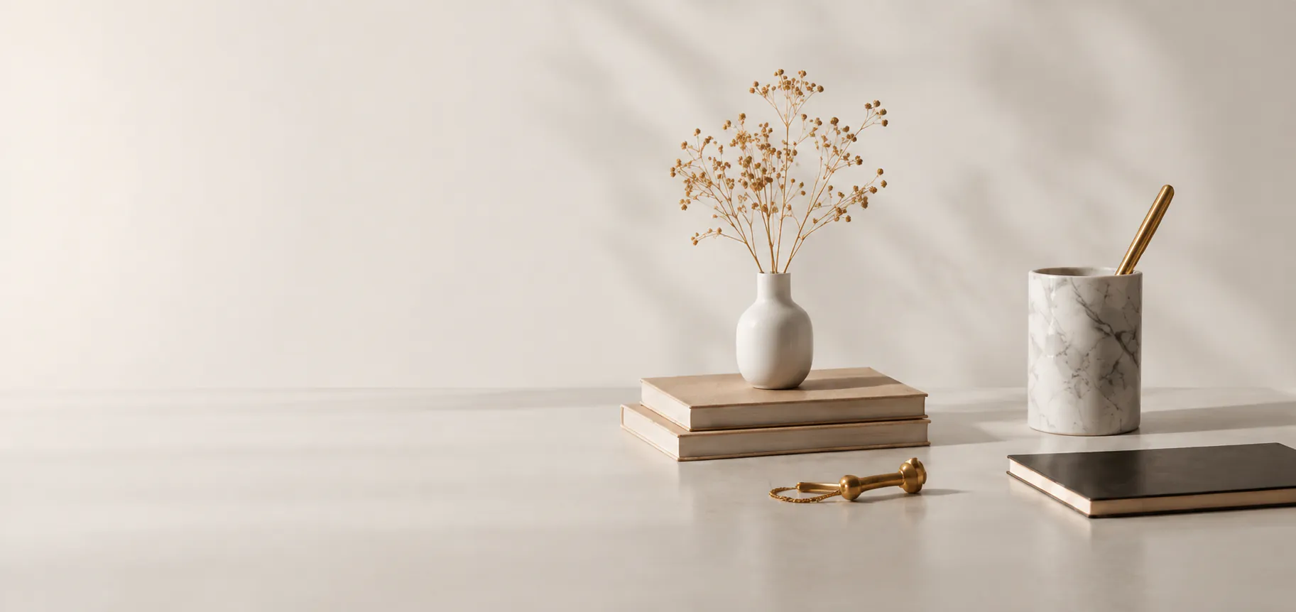 Dried flowers, books and a marble stand on a desk